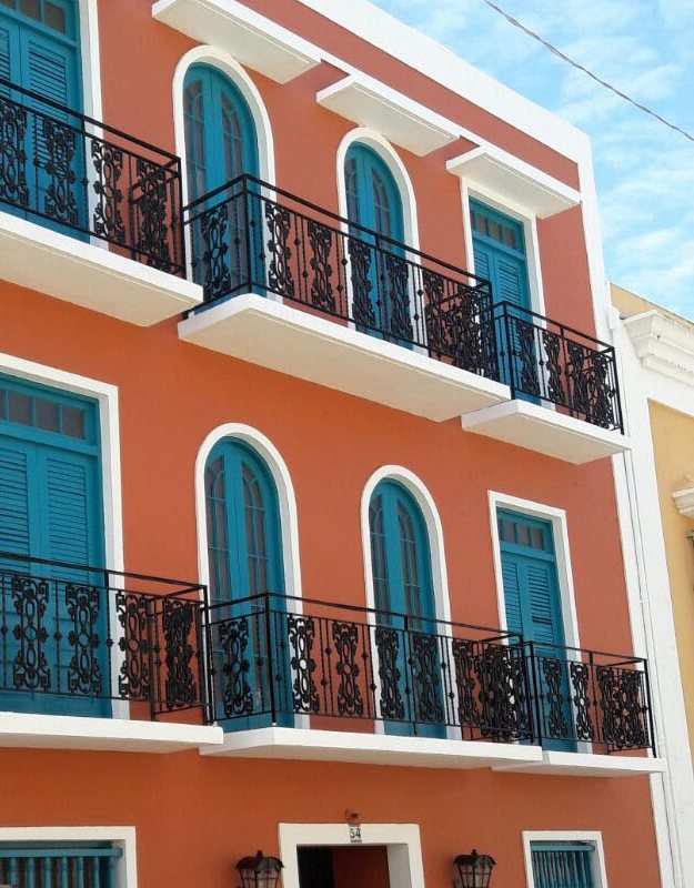 Fachada naranja con contraventanas verde azulado